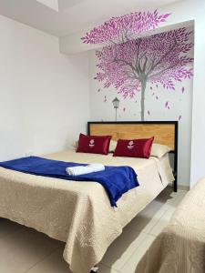 Hostal Amanari في بوبايان: غرفة نوم مع سرير كبير مع شجرة أرجوانية على الحائط