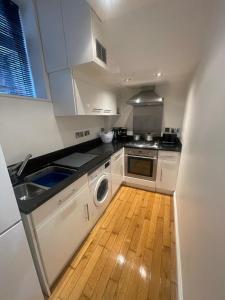 uma cozinha com armários brancos e piso em madeira em Central Windsor em Windsor