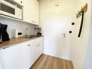 a kitchen with white cabinets and a sink and a refrigerator at Ferien im Wangerland - Haus Wiesenweg - Apartment 2 1OG in Wangerland