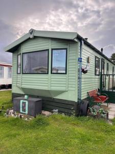 a green tiny house sitting in the grass at Red Lion Caravan Park, Arbroath in Arbroath