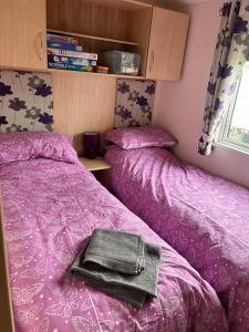 um quarto com 2 camas com lençóis roxos e uma bolsa em Red Lion Caravan Park, Arbroath em Arbroath