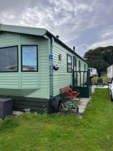 a green trailer sitting on the grass in a yard at Red Lion Caravan Park, Arbroath in Arbroath