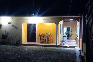 a house with a yellow wall and a patio at night at Casa Villa Flores in San Martín Zapotitlán