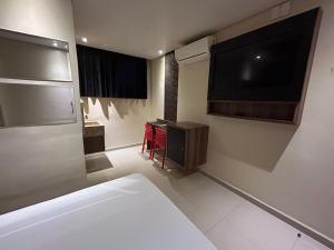 ein Schlafzimmer mit einem großen TV und einem Bett in der Unterkunft Só Love Hotel in São Paulo