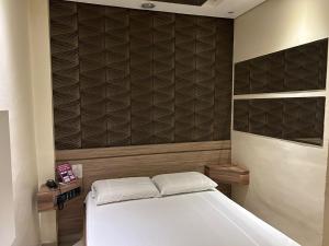 um quarto com uma cama branca e uma parede castanha em Só Love Hotel em São Paulo