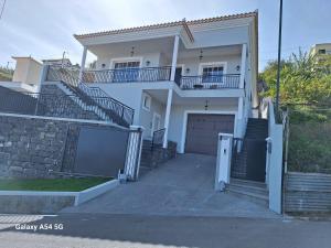 a white house with a gate and a garage at Figueira's House By the Atlantic in Ponta do Sol