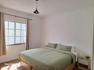 biała sypialnia z łóżkiem i oknem w obiekcie Figueira's House By the Atlantic w mieście Ponta do Sol
