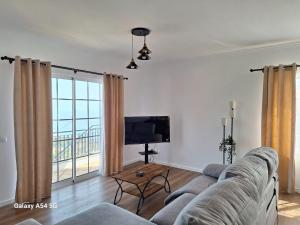 a living room with a couch and a tv at Figueira's House By the Atlantic in Ponta do Sol