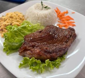 a plate of food with meat and rice and vegetables at Só Love Hotel in São Paulo