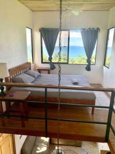 a swing bed in a room with windows at Cotinga Nest - King Bed, Ocean View in San Pedrillo