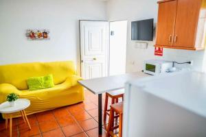 sala de estar con sofá amarillo y mesa en Acogedora casita, en El Charco