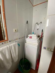 a bathroom with a pile of towels on a refrigerator at Acogedora casita in El Charco