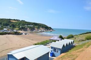 a view of a beach with blue buildings and the ocean at Pabell Pren Glamping - by Aberporth Beach Holidays in Aberporth +8 photos