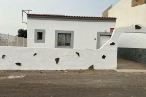 una pared con agujeros delante de un edificio en Acogedora casita, en El Charco