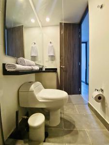 a bathroom with a toilet and a sink and a mirror at Apto pent-house amoblado para estrenar in Bogotá