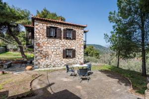 an external view of a stone house with a table and chairs at Elli Cottage in Skopelos Town