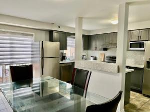 a kitchen with a glass table and a refrigerator at House In Scarborough 20 Minutes to Downtown in Toronto