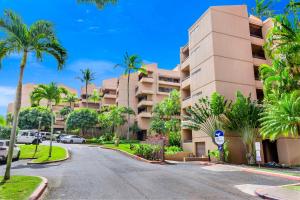 a street in front of a building with palm trees at Kahana Villa in Lahaina