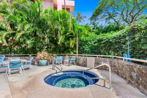 a hot tub in a patio with chairs and a table at Kahana Villa in Lahaina +2 photos