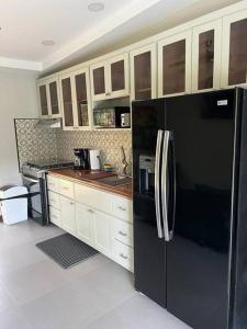 a kitchen with a black refrigerator and white cabinets at Chabayali House in San Juan del Sur