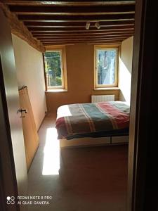 1 dormitorio pequeño con 1 cama y 2 ventanas en Ancienne ferme totalement rénové moderne à Baelen, en Baelen
