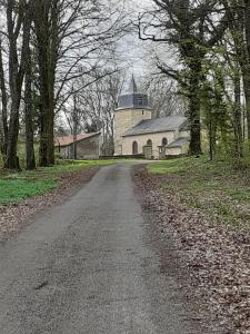 a dirt road leading to a building with a tower at A l'OREE DU BOIS in Ville-Houdlémont