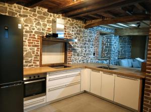 cocina con armarios blancos y pared de piedra en Ancienne ferme totalement rénové moderne à Baelen, en Baelen