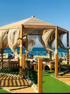 einen hölzernen Pavillon am Strand mit Meer in der Unterkunft Tavira شاليه in Ras Sudr