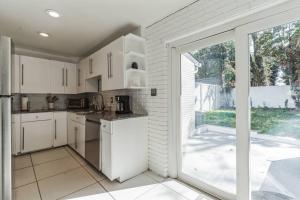 a kitchen with white cabinets and a large sliding glass door at Beltline Beauty*Mins to Benz Stadium, Game Room* in Atlanta