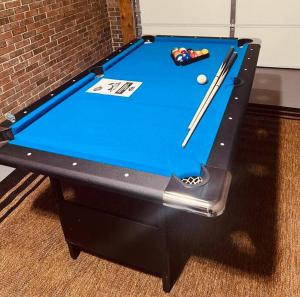 a blue pool table with two cuesticks on it at Beltline Beauty*Mins to Benz Stadium, Game Room* in Atlanta