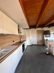 una cucina con armadi bianchi e soffitto in legno di Grazioso appartamento ad Aosta