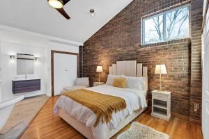 a bedroom with a brick wall and a large bed at Beltline Beauty*Mins to Benz Stadium, Game Room* in Atlanta