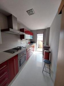 a kitchen with red cabinets and a chair in it at Disfrutar de la playa in Playa de Gandia