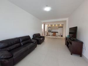 a living room with a leather couch and a flat screen tv at Linda cobertura Prainha de Mambucaba Paraty 50m da praia in Paraty