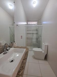 a white bathroom with a sink and a toilet at Linda cobertura Prainha de Mambucaba Paraty 50m da praia in Paraty +14 photos