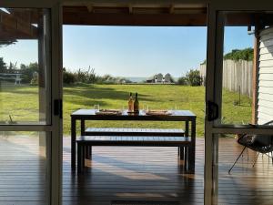 a table on a porch with a view of a yard at Beachfront Retreat On Revell in Hokitika