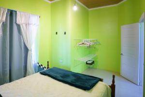 een groene slaapkamer met een bed en een raam bij Root Wellness Arenal in Esperanza