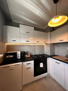 a kitchen with white cabinets and a black stove top oven at Apartament Center Starowiślna in Krakow