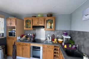 cocina con armarios de madera y encimera negra en Family nest located in Hermanville-sur-mer, en Hermanville-sur-Mer