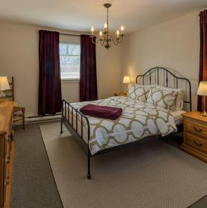 Un dormitorio con una cama grande y una lámpara de araña. en Le toit bleu, en North Hatley