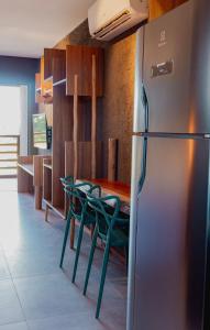 a kitchen with green chairs and a refrigerator at Condomínio Gamboa Patacho a 190 da praia na Rota dos Milagres in Pôrto de Pedras