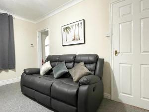 - un canapé en cuir noir dans le salon dans l'établissement Cosy home, family & contractor friendly 4 bedroom near Leeds centre, sleeps 7, à Leeds