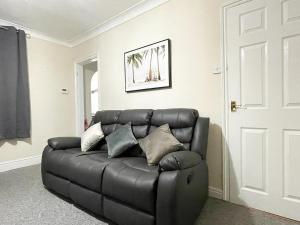 a black leather couch sitting in a living room at Cosy home, family & contractor friendly 4 bedroom near Leeds centre, sleeps 7 in Leeds