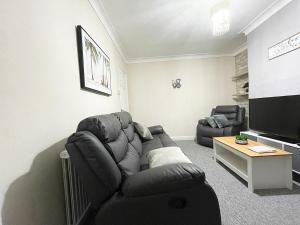 Il comprend un salon doté d'un canapé et d'une télévision à écran plat. dans l'établissement Cosy home, family & contractor friendly 4 bedroom near Leeds centre, sleeps 7, à Leeds