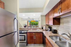 a kitchen with wooden cabinets and a stainless steel refrigerator at Kahana Villa in Lahaina