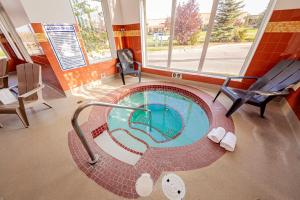 una pequeña piscina en una habitación con silla en Service Plus Inns and Suites Calgary, en Calgary