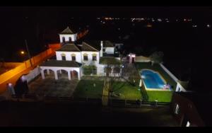una gran casa blanca con techo verde por la noche en Villa Cortijo El Torreon, en Utrera