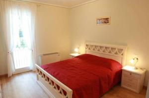 1 dormitorio con cama roja y ventana en Villa delle Rose, en Portogruaro