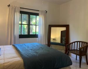 ein Schlafzimmer mit einem Bett, einem Spiegel und einem Stuhl in der Unterkunft Macondo entre cerros y mar in Piriápolis