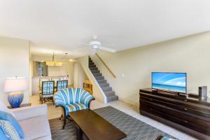 a living room with a tv and a couch at Kahana Villa in Lahaina